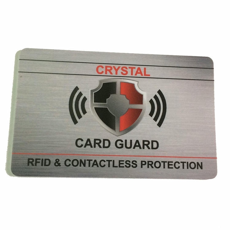 Card de blocare argintiu RFID etichetat Crystal Card Guard cu scut și pictograme unde radio care evidențiază RFID și protecția fără contact.