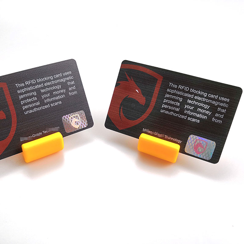 Două carduri de blocare RFID cu text de securitate și logo-ul scutului roșu afișat pe suport galben pentru fotografia de produs a cardurilor de protecție a călătoriei.