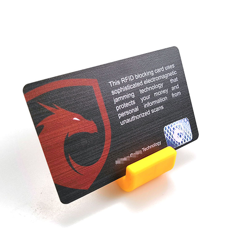 Un singur card de blocare RFID cu emblema scutului roșu și mesaj de protecție prezentat pe un suport galben pe un fundal alb curat.