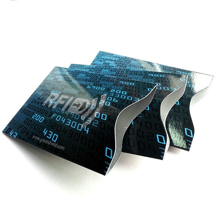 Vedere în unghi a trei mâneci de blocare RFID cu model albastru stivuite împreună pentru a evidenția deschiderea laterală ondulată pentru cărți.
