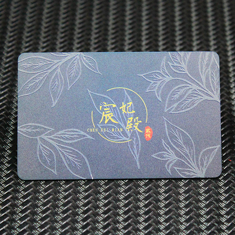 Carte de vizită metalică premium albastră, cu gravură tip frunze și text auriu central, prezentând un card rafinat de membru VIP.