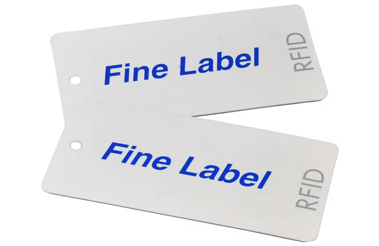 Două etichete textile RFID albe pentru haine, imprimate cu marca Fine Label, care ilustrează un stil curat de etichetă vestimentară personalizată.
