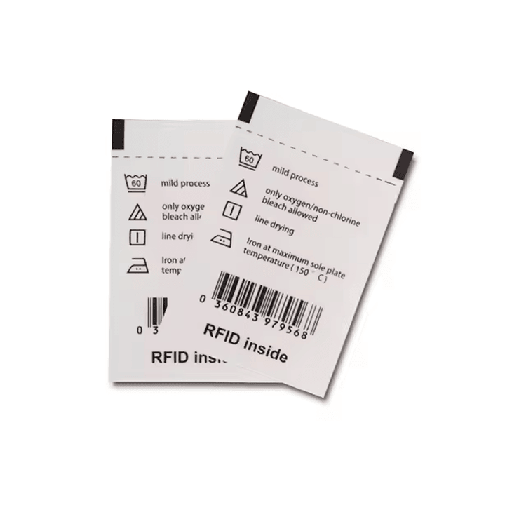 O imagine de produs curată arată două etichete albe RFID pentru articole de îmbrăcăminte textile imprimate cu simboluri de îngrijire și detalii coduri de bare pentru urmărirea îmbrăcămintei.