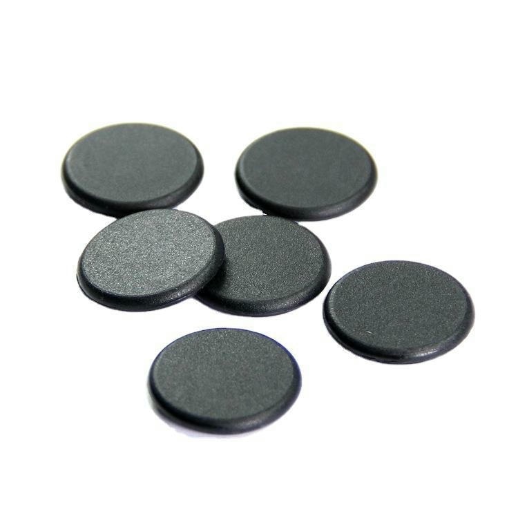 Vedere în unghi a mai multor discuri negre de tag RFID PPS model PPSD30-1, ilustrând profilul rotund pentru integrare în textile sau suporturi.