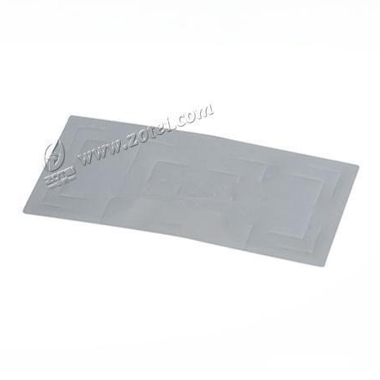 Sticker RFID dreptunghiular gri pentru parbriz, fotografiat pe fundal alb, cu modelul antenei embosate evidențiat pentru identificarea vehiculelor.
