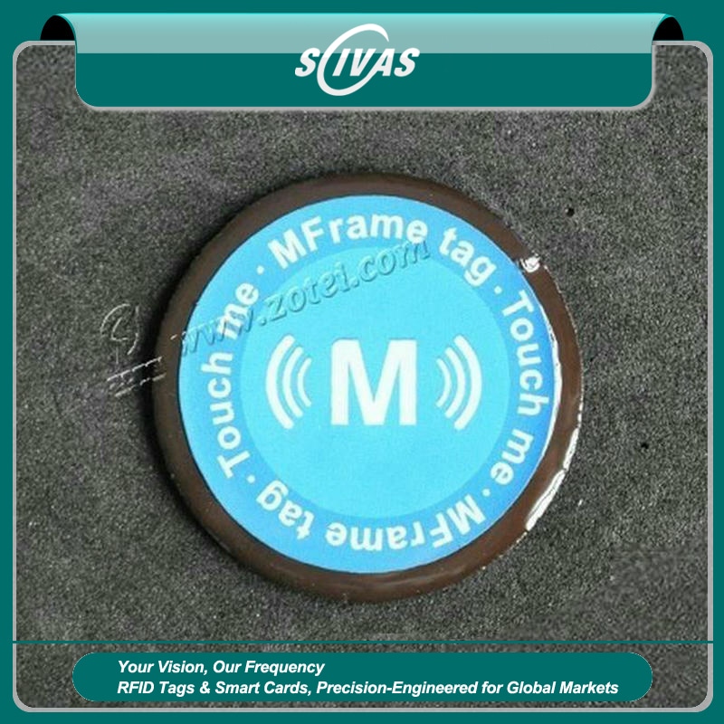 Eticheta D40mm epoxidică antimetal RFID este prezentată ca o etichetă rotundă albastră fixată pe o suprafață metalică închisă la culoare; cu o margine de protecție lucioasă.