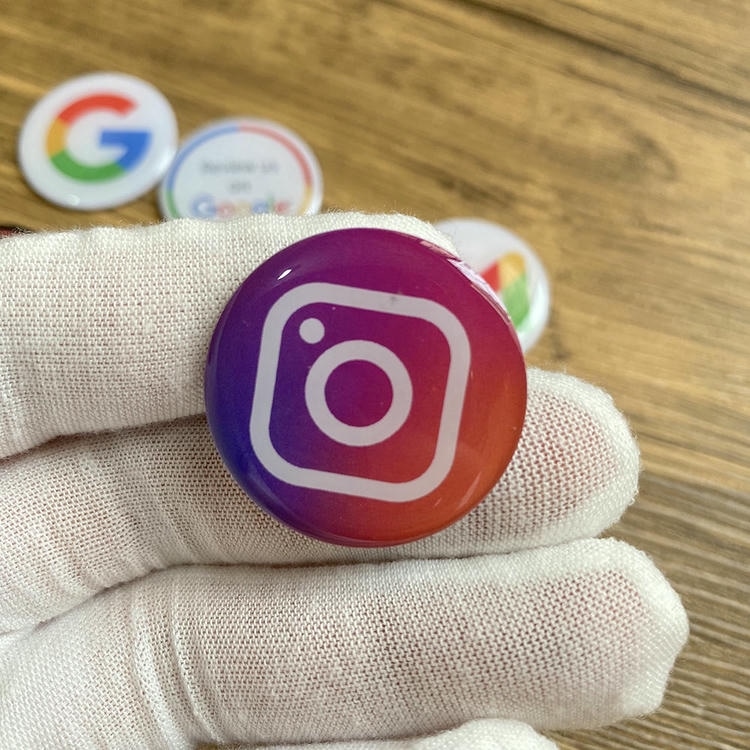Autocolant epoxidic NFC cu formă personalizată; ținut cu o mână înmănușată; care arată o insignă în stil Instagram cu dom epoxidic pentru partajare rapidă prin atingere.